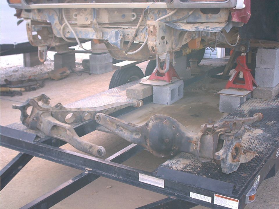 Front axle assembly and suspension components removed from a vehicle, resting on a trailer