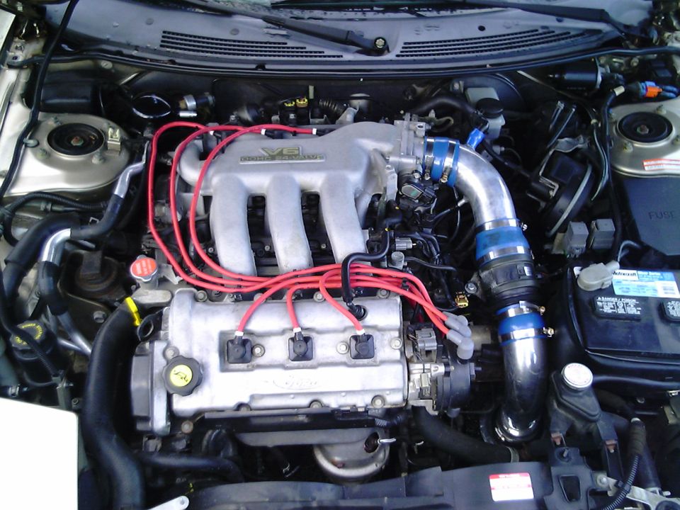 1997 Ford Probe engine bay with V6 intake manifold, red spark plug wires, and blue intake piping