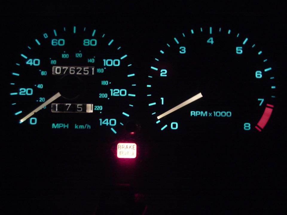 Car dashboard with speedometer showing 75 MPH and tachometer at 1000 RPM. Odometer reads 076251. Brake light is illuminated