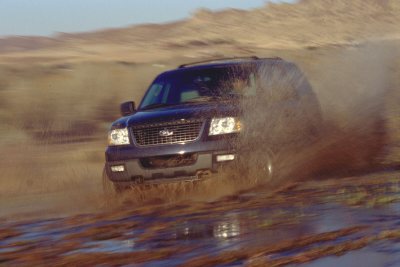2003 Ford Expedition - A 2003 Ford Expedition navigates a muddy terrain, kicking up water.