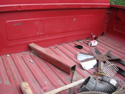 1974 Ford F-100 - Contents of a red pickup truck bed, including a metal tube and fan parts.