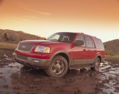 2003 Ford Expedition - A red 2003 Ford Expedition navigates a muddy terrain, its off-road capabilities.