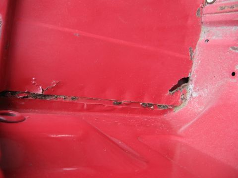 1974 Ford F-100 - This image shows significant rust damage on a red metal panel, indicating structural wear.