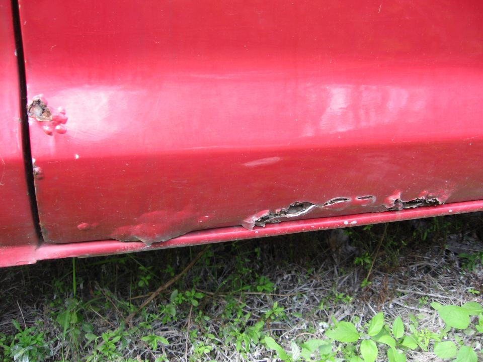 close-up of rusted lower body panel on red truck