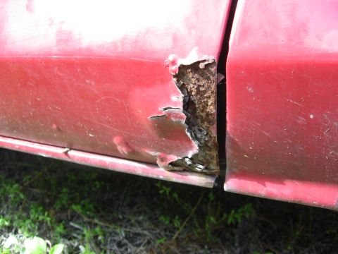 1974 Ford F-100 - Extensive rust has compromised the lower section of this red truck's door panel.