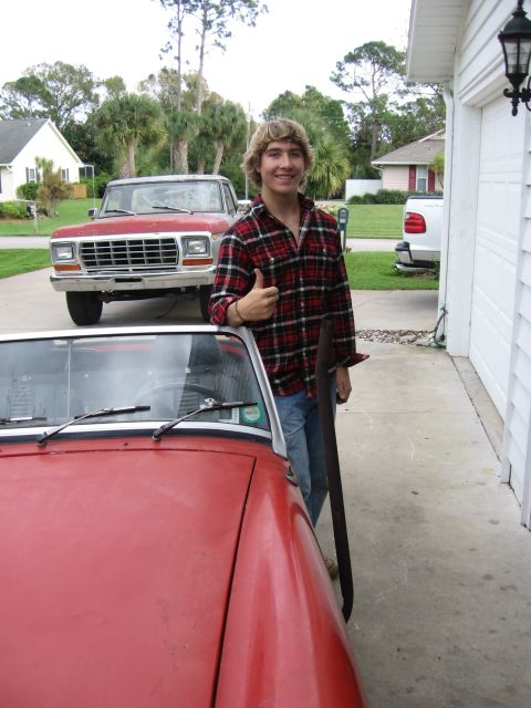 1974 Ford F-100 - A young man poses with a red convertible, a red pickup truck behind him.