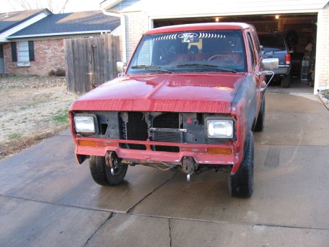 1984 Ford Bronco II - Front view of a red 1984 Ford Bronco II undergoing repairs, with its grille and bumper removed.