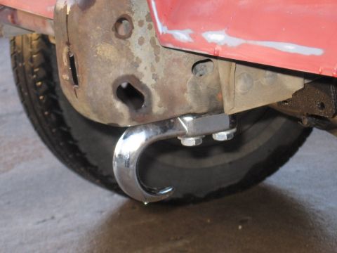 1984 Ford Bronco II - A close-up view of a chrome tow hook attached to the frame of a vehicle, with a tire visible in the background.