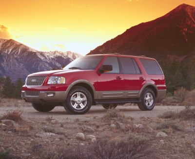2003 Ford Expedition - A red 2003 Ford Expedition SUV is parked on a dirt road with mountains and a sunset in the background.