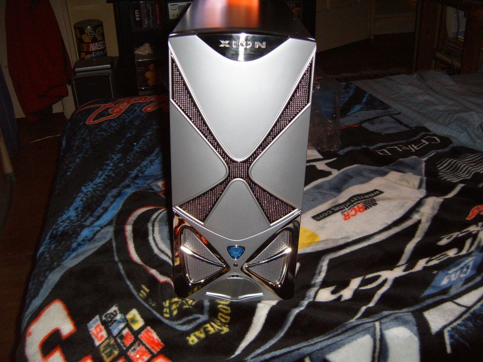 Silver computer tower with a black X design on the front, placed on a race car themed blanket