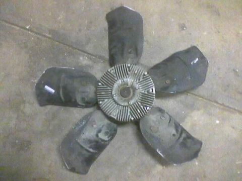 1989 Ford Bronco - A radiator fan with five black blades and a silver hub is shown lying on a concrete surface.