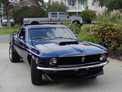 1970 Ford Mustang - Blue 1970 Ford Mustang coupe parked outside, with a grey pickup truck in the background.