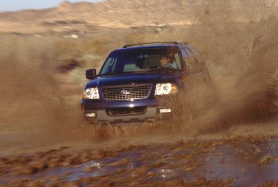 2003 Ford Expedition - Ford Expedition navigating a muddy trail, kicking up dirt and water.