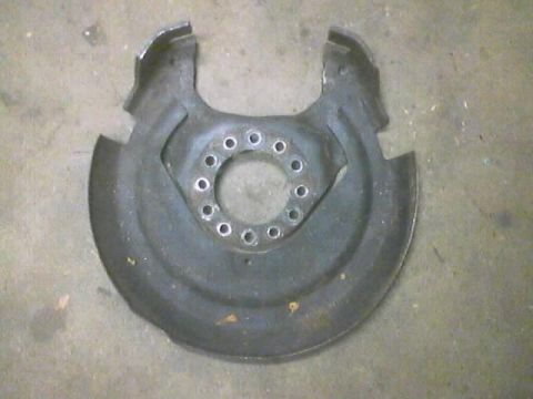 1989 Ford Bronco - A metal brake dust shield, likely from a truck or SUV, is shown against a concrete floor.