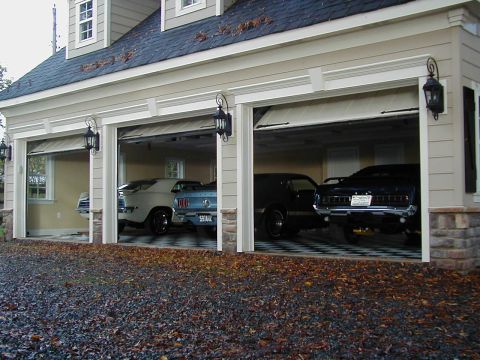 1970 Ford Mustang - A garage houses three vintage automobiles, each with a distinct color and style, parked on a checkered floor.