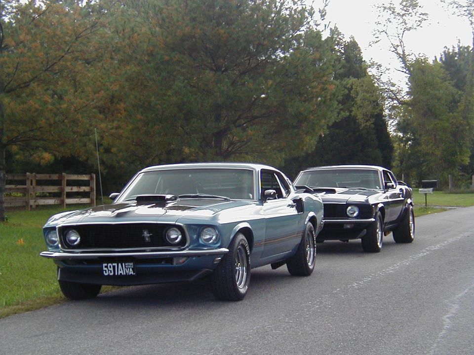 Blue 1969 Ford Mustang with hood scoop and license plate 597ANV, parked on asphalt road
