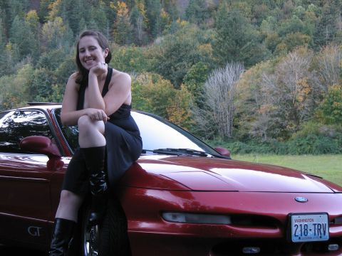 1997 Ford Probe - Woman poses with a red 1997 Ford Probe GT in front of a wooded hillside.
