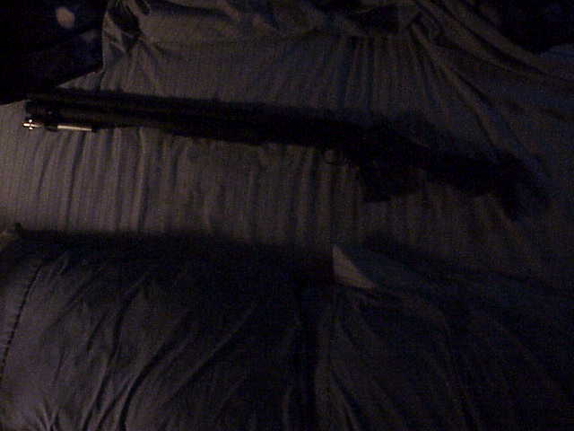 Black shotgun lying on dark fabric