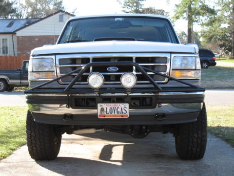 1994 Ford Bronco - Frontal view of a white Ford Bronco with a custom bumper and auxiliary lights, parked on a driveway.