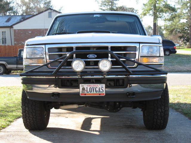 Front view of lifted white Ford with brush guard, driving lights and LOVGAS Virginia plate