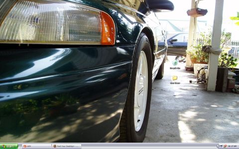 1993 Ford Taurus - Close-up of a green 1993 Ford Taurus, showing the front headlight and wheel detail.