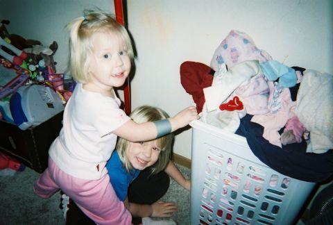 2002 Oldsmobile Aurora - Two young children are playing near a laundry basket filled with clothes.