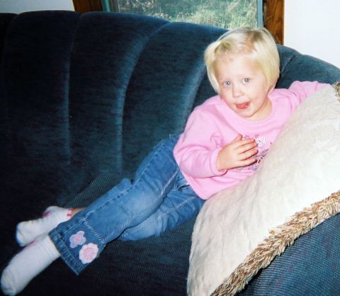 2002 Oldsmobile Aurora - A young child sits on a couch, looking towards the camera.