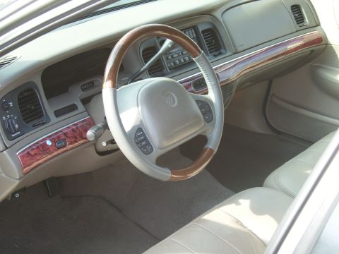 2000 Mercury Grand Marquis - Interior view of a 2000 Mercury Grand Marquis, highlighting the steering wheel and dashboard with wood trim accents.