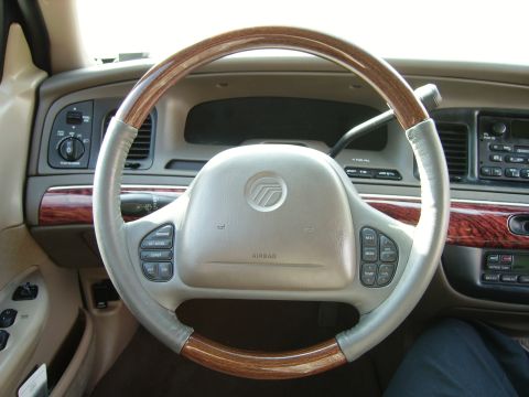 2000 Mercury Grand Marquis - The steering wheel of a 2000 Mercury Grand Marquis features wood grain accents and integrated controls.