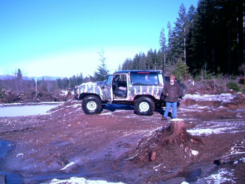 1987 Ford Bronco II - 1987 Ford Bronco II in a wooded area with camouflage paint and snow on the ground.