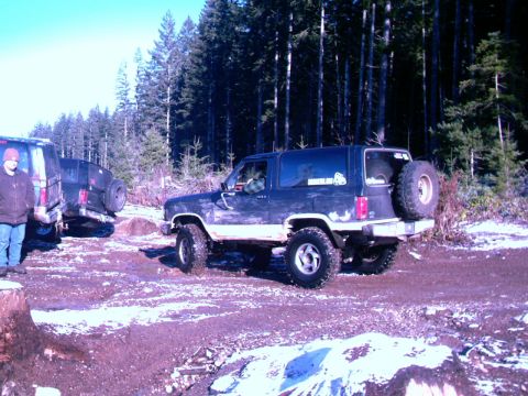 1987 Ford Bronco II - A group of off-road vehicles are parked in a snowy, wooded area, with one Bronco II prominently featured.