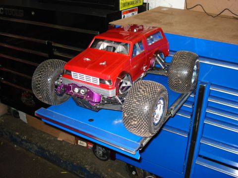 1994 Ford Bronco - This red remote control truck features oversized tires and custom purple suspension parts, resembling a Bronco body style.