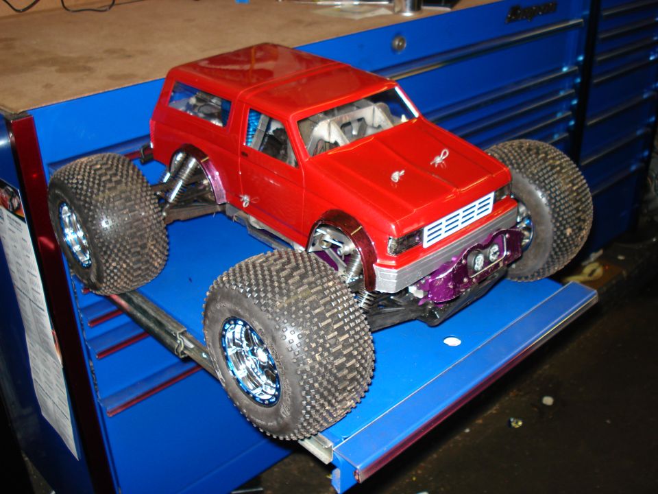 Red remote control monster truck with large tires on a blue surface