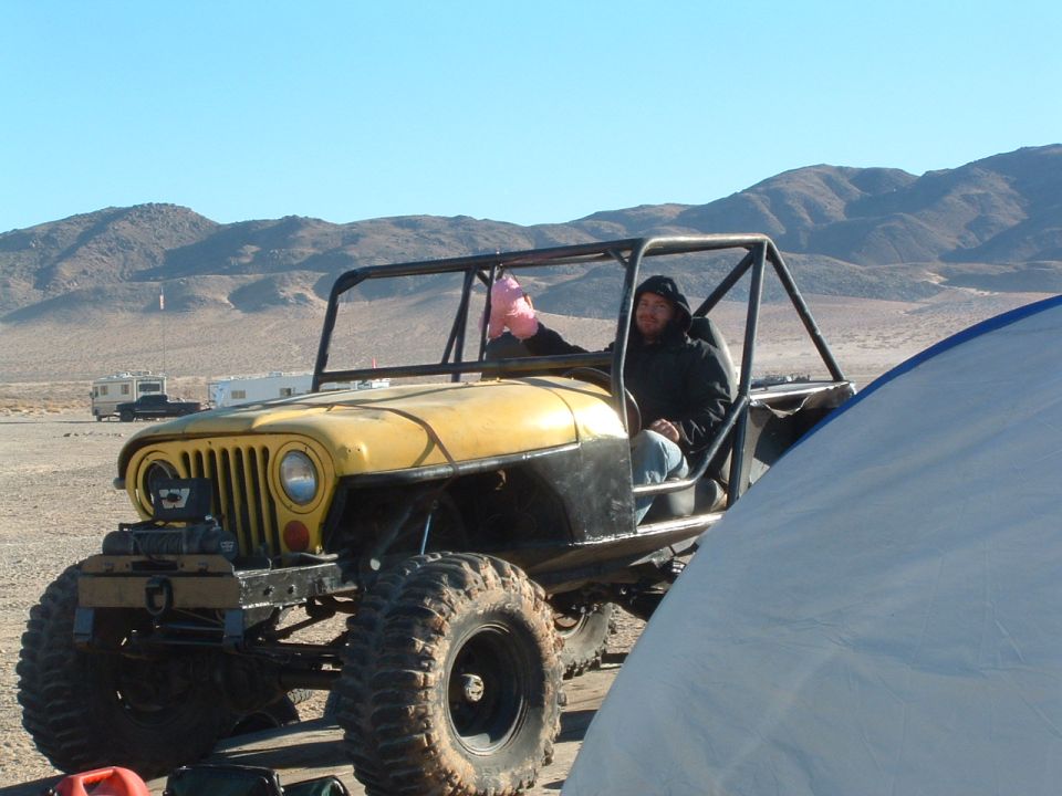 Yellow 1994 Jeep YJ with roll cage and large tires in desert