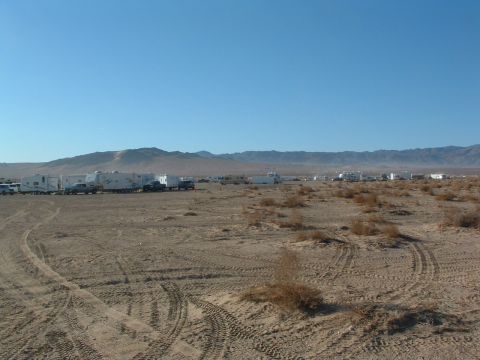 1994 Jeep YJ - A large gathering of vehicles, including RVs and trucks, are parked in a desert area with mountains in the background.