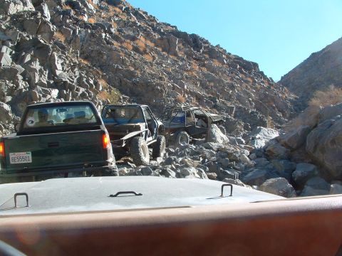 1994 Jeep YJ - Off-road vehicles navigating a challenging rocky canyon trail under a clear blue sky.