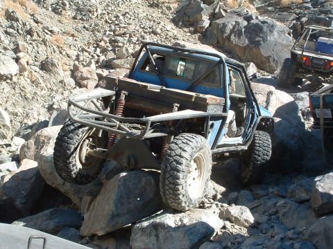 1994 Jeep YJ - This heavily modified buggy navigates a challenging rocky trail, with other off-road vehicles visible in the background.