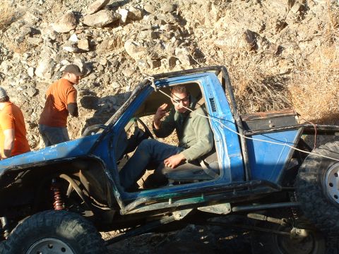 1994 Jeep YJ - Modified off-road truck with people on rocky terrain, driver visible inside the cab.