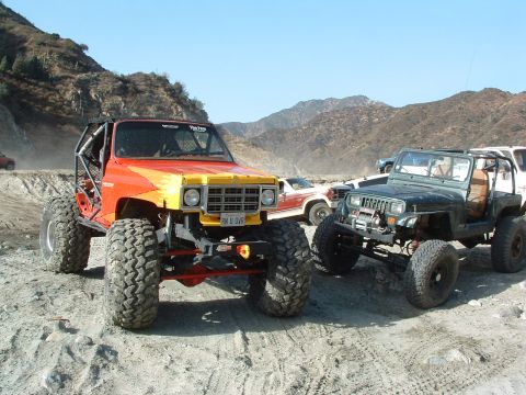 1994 Jeep YJ - Two heavily modified Jeeps, one a 1994 YJ, are parked off-road in a dusty, mountainous area.