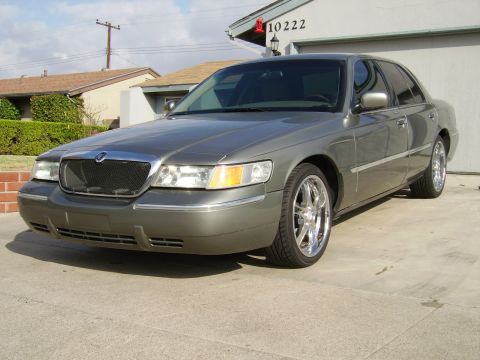 2000 Mercury Grand Marquis - Gray 2000 Mercury Grand Marquis with aftermarket wheels parked in front of a house.