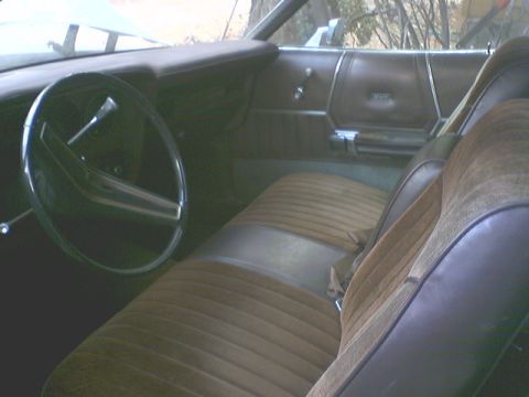1973 Ford Ranchero - The interior of a 1973 Ford Ranchero features brown velour seats and door panels, with a prominent two-spoke steering wheel.
