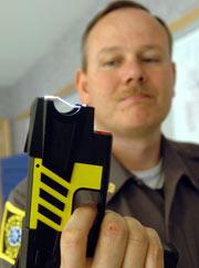 1998 Ford Crown Victoria - Officer holds a taser, a non-lethal weapon, in a close-up shot.