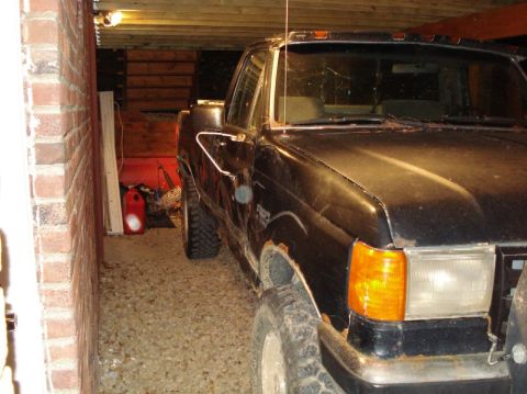 1989 Ford F-250 - Black Ford F-Series truck parked in a garage, showing front quarter panel and side.