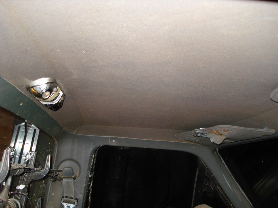 Interior shot of a vehicle's headliner with a dome light and some rust damage