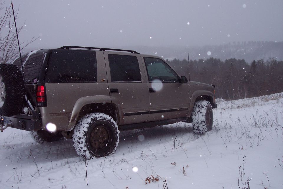 tan SUV with spare tire on back driving in snow