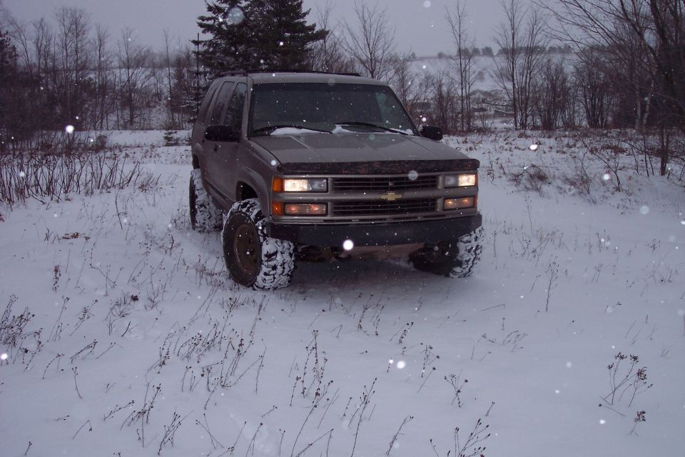 Brown Chevrolet Tahoe with large tires in snow, front view
