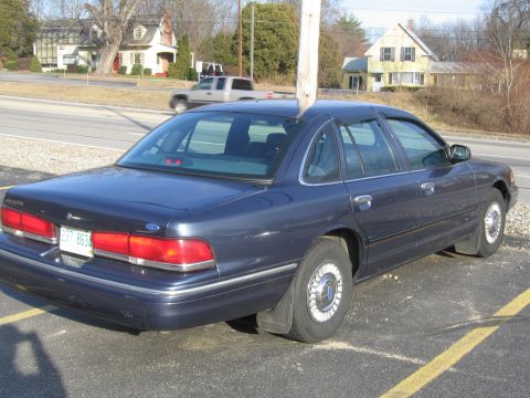 1991 Ford LTD Crown Victoria - A dark blue sedan is parked on asphalt, with a utility pole behind it.