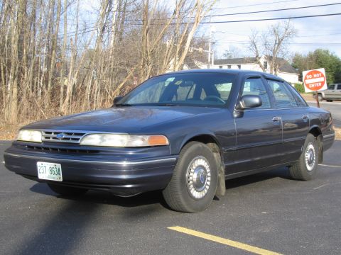 1991 Ford LTD Crown Victoria - A dark blue sedan is parked in a lot with trees and a 'Do Not Enter' sign visible.