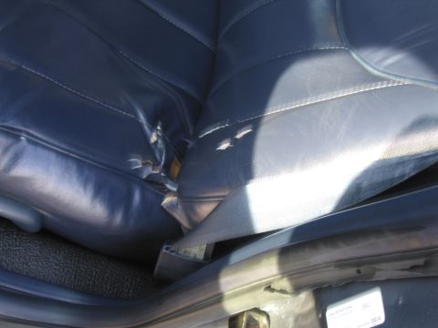 1991 Ford LTD Crown Victoria - The interior of a vehicle shows a damaged blue leather seat with a visible seatbelt.