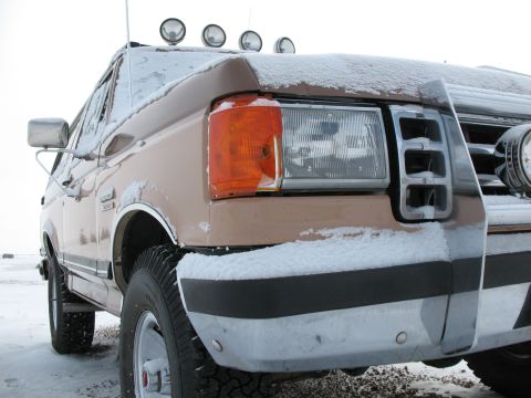 1989 Ford Bronco - A brown Ford Bronco covered in snow is viewed from a low 3/4 front angle.